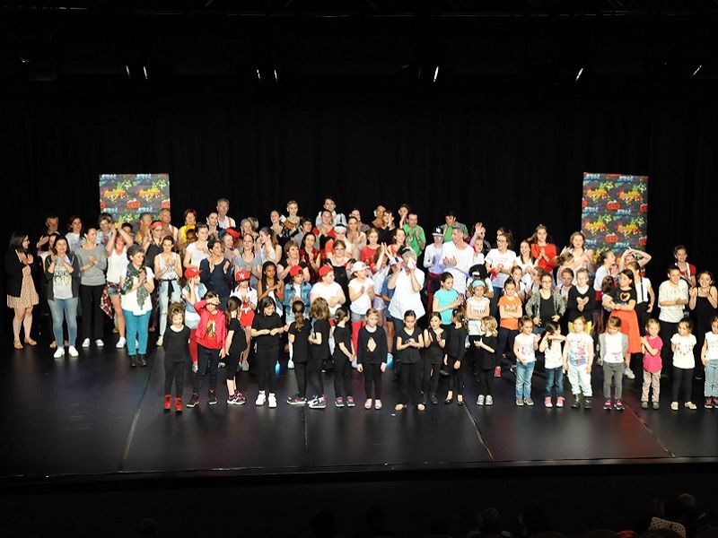 Les adhérents de tous âges réunis sur une scène, pour une photo de groupe.
