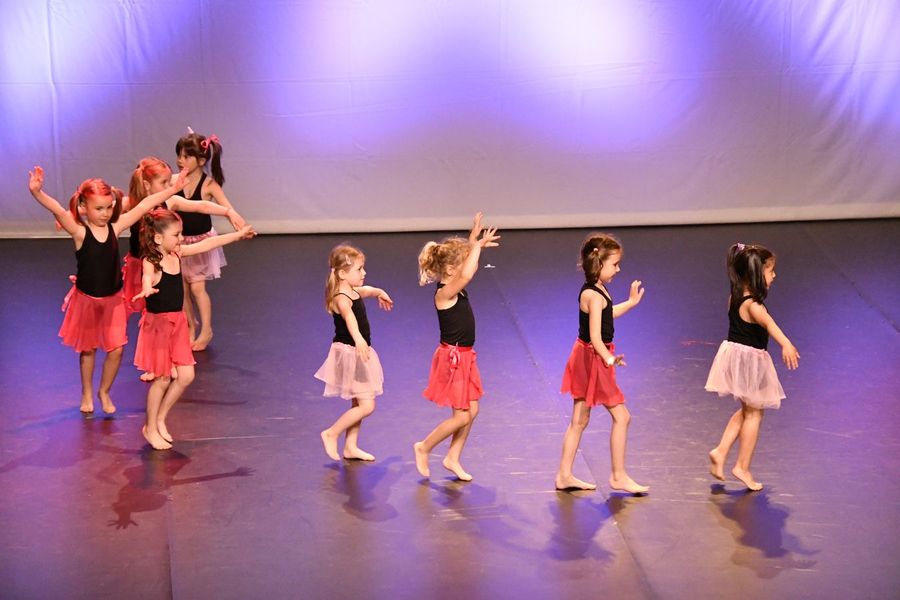 De très jeunes danseuses en jupons rouges et roses traversent la scène.