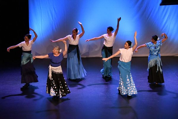 Le groupe de flamenco, bras levés, sous une lumière bleue.