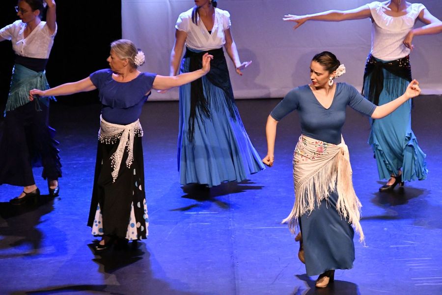 Des danseuses de flamenco en jupes bleues et châles à franges, bras ouverts.