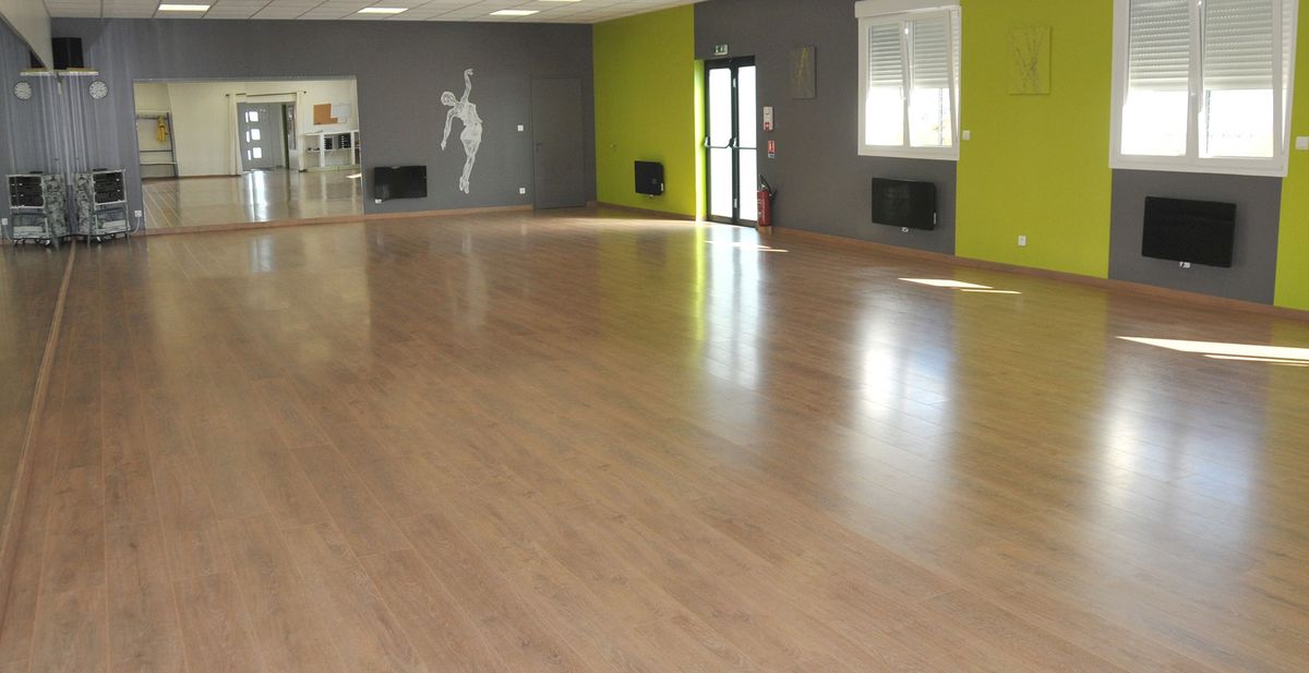 La salle de danse vide : un grand parquet, des miroirs et de larges fenêtres.